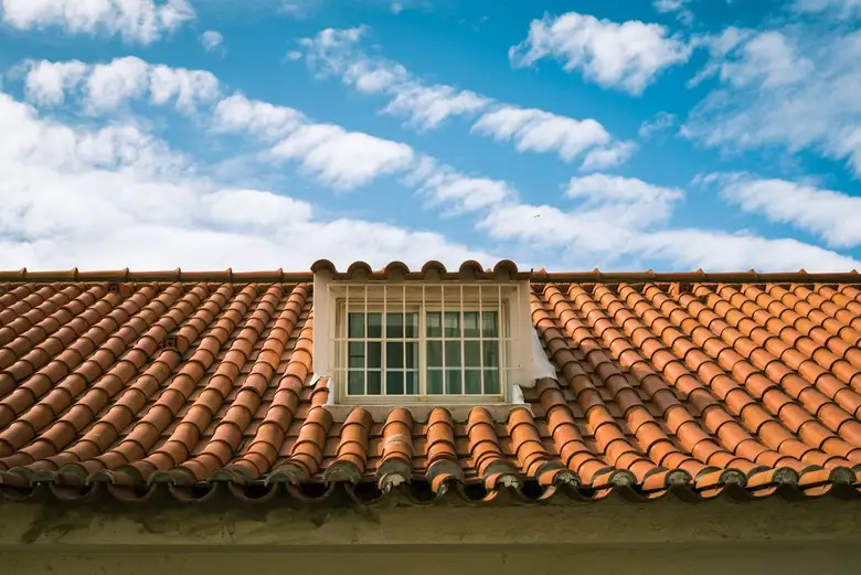 Terracotta tiled roof with a skylight window in bright sun