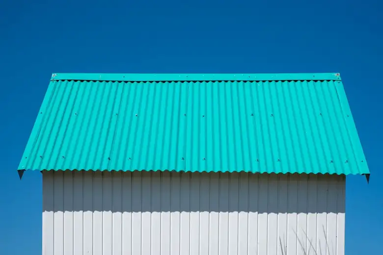 Corrugated metal roof sheeting against a white gable wall